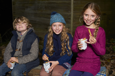 Lächelnde Kinder, die nachts Pommes frites essen, lizenzfreies Stockfoto