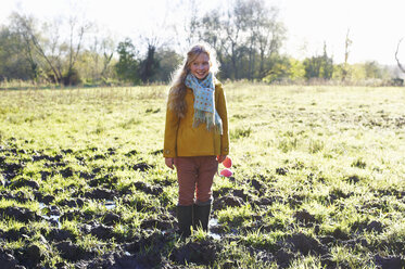 Smiling girl standing in muddy field - CAIF00928