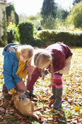 Girls petting dog in autumn leaves - CAIF00941