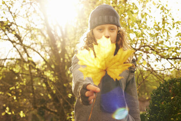 Girl holding autumn leaf outdoors - CAIF00953