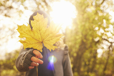 Boy holding autumn leaf outdoors - CAIF00963