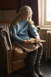 Mädchen liest Buch im Sessel - CAIF00976