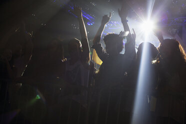 Scheinwerferlicht über der Silhouette einer jubelnden Menge bei einem Konzert - CAIF01076