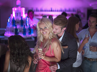 Porträt eines lächelnden Paares mit Cocktails in einem Nachtclub - CAIF01083