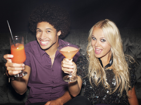 Portrait of enthusiastic couple toasting cocktails in nightclub stock photo