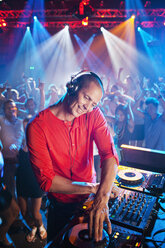 DJ am Plattenteller mit Publikum auf der Tanzfläche im Hintergrund - CAIF01095