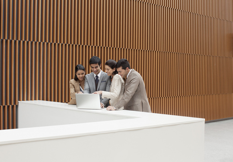 Geschäftsleute mit Laptop am Sims im Büro, lizenzfreies Stockfoto