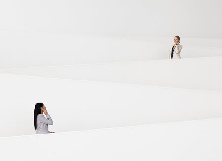 Geschäftsfrauen, die auf einer modernen Treppe mit Handys telefonieren - CAIF01148