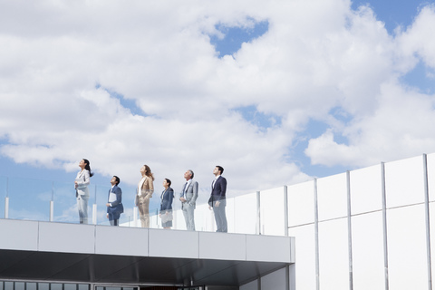 Geschäftsleute auf einem Dachbalkon mit Blick in den Himmel, lizenzfreies Stockfoto