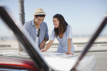 Lächelndes Paar liest Straßenkarte auf Cabrio - CAIF01156