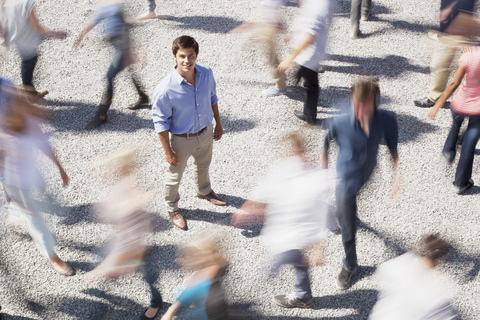 Portrait of smiling businessman surrounded by people rushing by stock photo