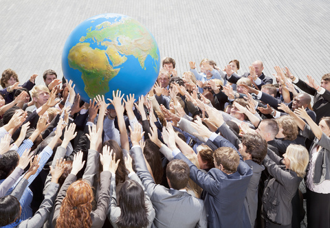 Crowd of business people reaching for globe stock photo