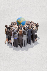 Eine Gruppe von Geschäftsleuten drängt sich zusammen und hebt einen Globus über den Kopf - CAIF01221