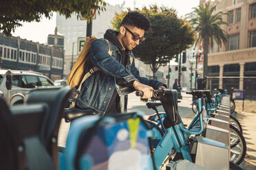 Stylish young man on the street with rental bike - SUF00471