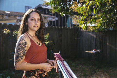 Portrait of young woman with tattoo in backyard stock photo