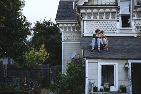 Couple sitting on roof kissing - SUF00518