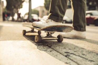 Close-up of man with skateboard on sidewalk - SUF00528