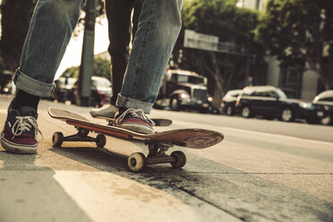 Close-up of man with skateboard on sidewalk - SUF00529