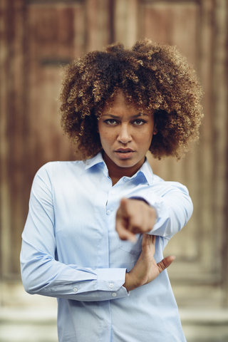 Porträt einer ernsten Frau mit Afrofrisur, die mit ihrem Finger auf etwas im Freien zeigt, lizenzfreies Stockfoto