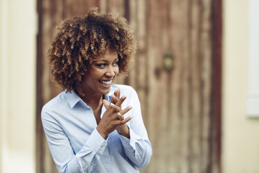 Laughing woman with afro hairstyle outdoors looking sideways - JSMF00034