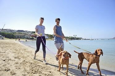 Junges Paar, das mit Hund am Strand spazieren geht - ECPF00180