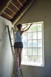 Young woman renovating her home working at window frame - ECPF00187