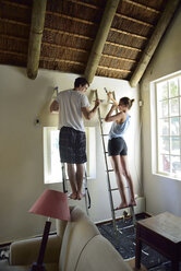 Young couple renovating their home painting the wall together - ECPF00188