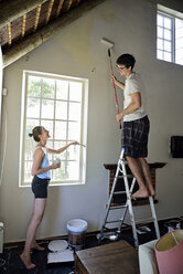 Young couple renovating their home painting the wall together - ECPF00192
