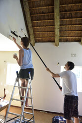 Young couple renovating their home painting the wall together - ECPF00196
