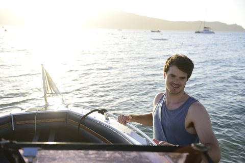 Lächelnder junger Mann auf einem Boot auf dem Meer, lizenzfreies Stockfoto