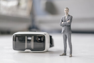 Miniature businessman figurine standing next to VR glasses - FLAF00140