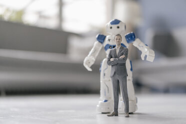 Miniature businessman figurine standing in front of robot - FLAF00143