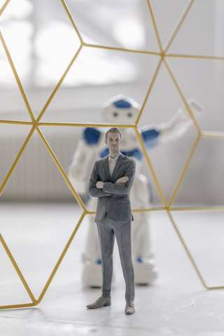 Miniature businessman figurine standing in front of robot seperated by structure stock photo