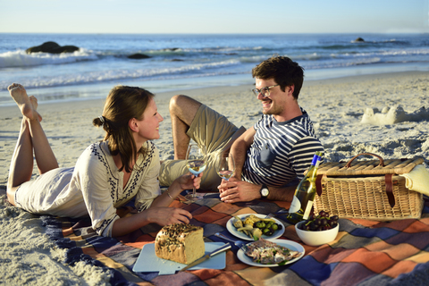 Glückliches Paar beim Picknick am Strand, lizenzfreies Stockfoto