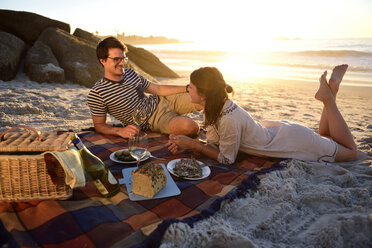 Glückliches Paar beim Picknick am Strand bei Sonnenuntergang - ECPF00215