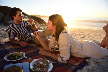 Glückliches Paar beim Picknick am Strand bei Sonnenuntergang - ECPF00216