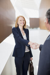 Lächelnde Geschäftsfrau schüttelt Hände mit Geschäftsmann - CAIF01265