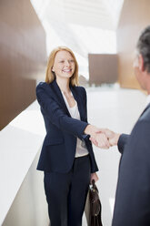 Smiling businesswoman shaking hands with businessman - CAIF01265