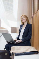 Porträt einer lächelnden Geschäftsfrau mit Laptop - CAIF01283