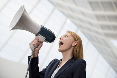 Businesswoman shouting into bullhorn - CAIF01311