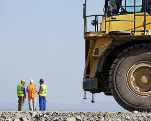 Workers talking with machinery in quarry - CAIF01329