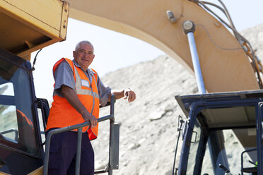 Arbeiter, der auf einer Maschine auf der Baustelle steht - CAIF01371