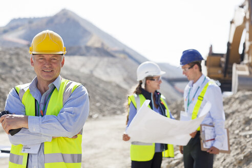 Businessman in hard hat smiling in quarry - CAIF01382