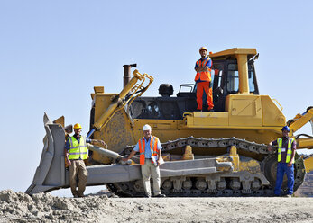 Workers on bulldozer smiling in quarry - CAIF01383