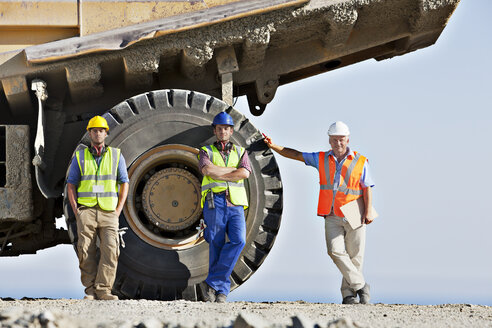 Arbeiter, die auf der Baustelle an Maschinen stehen - CAIF01387