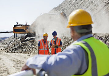 Businessman watching workers in quarry - CAIF01392