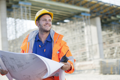 Arbeiter beim Lesen von Bauplänen auf der Baustelle - CAIF01433