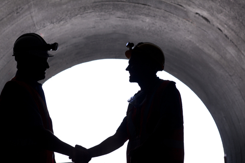 Silhouette von Arbeitern beim Händeschütteln im Tunnel, lizenzfreies Stockfoto