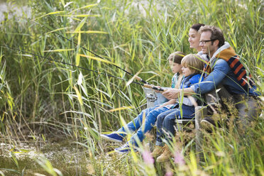 Familie beim gemeinsamen Angeln im hohen Gras - CAIF01455