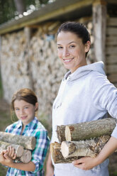 Mutter und Tochter tragen Brennholz ins Freie - CAIF01456